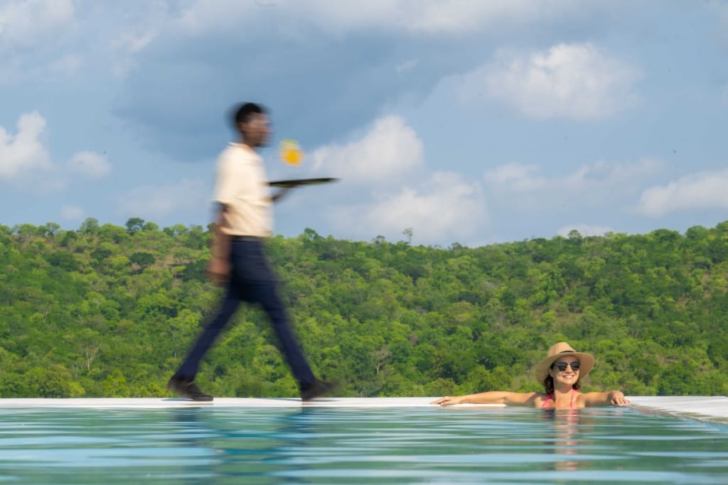 Pool attendant serving cocktail to a guest in the infinity pool
